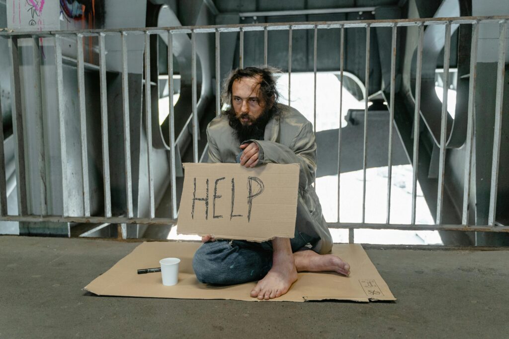 The Unhoused. A man with a cardboard sign that says help.